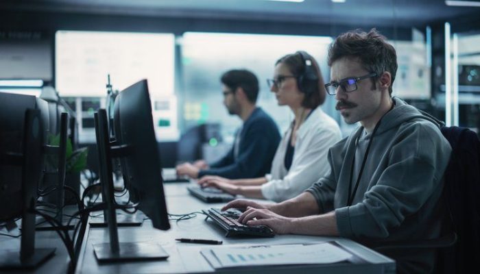 Three IT security professionals work on computers